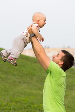 Parkta babası ile First Steps erkek bebek. Yazın bir sürü yeşil çimen ve ağaç etrafında.