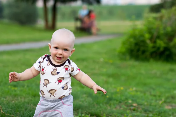 Sevimli bebek çocuk oynarken ve parkta gülüyor. Yaz kırıntıları için yeşillik ilginç şeyler bir sürü civarındadır. Çocuk 1 yıl