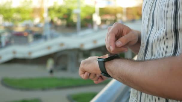 Außenporträt eines modernen jungen Mannes mit Smartwatch auf der Straße. vor dem Hintergrund von Menschen, die durch die Stadt gehen und schnell reden. Nahaufnahme — Stockvideo