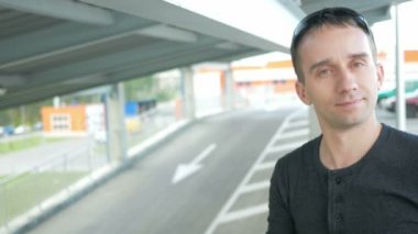 Genç yakışıklı adam bir güzel uygun giysiler kentsel peyzaj kamera gülümse. Yol ve sürücü araba arkasında