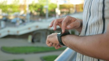 Sokakta akıllı saat ile modern genç adamın açık hava portresi. Arka planda yürüyen ve hızlı şehir hayatı konuşan insanlar karşı. Close