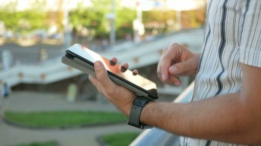 Sokakta dijital tablet ile modern genç adamın dış portre. Arka planda yürüyen ve hızlı şehir hayatı konuşan insanlar karşı. Close