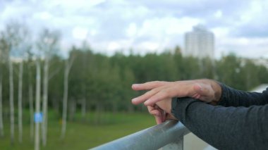 Modern genç adam akıllı saati olan açık portresi. Arka plan yeşil ağaçlar ve güzel mavi bulutlar karşı. Yakın çekim