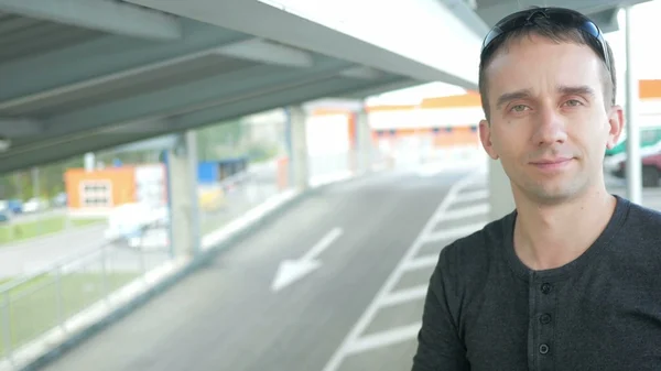 Genç yakışıklı adam bir güzel uygun giysiler içinde kaldırır ve güneş gözlüğü gülümseme takıyor. kentsel peyzaj
