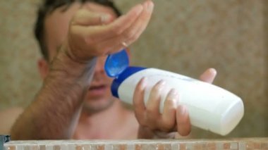 Bir adam otelde duş alıyor. O şampuan el dökülen, kafa sabunlar