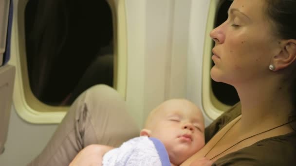 Mutter und Baby ruhen sich während des Fluges im Flugzeug aus. Nachtflug über den Ozean. Die Kinderaugen sind geschlossen — Stockvideo