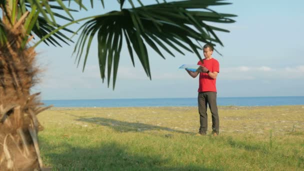 Muž na skalnatou pláž. Palma v popředí. Turisté hledají správné cestovní mapa — Stock video