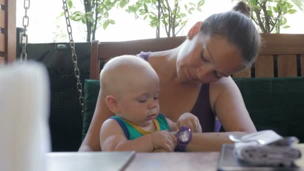 Maman et bébé sont venus au café et ont attendu la commande. Un gamin qui joue avec tout le monde. Enfant 1 an — Video