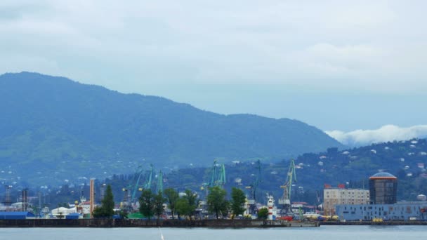 O porto fica perto do mar e das montanhas, que estão esperando por um navio. Nuvens espalhadas pelas montanhas — Vídeo de Stock