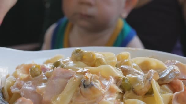 La joven madre está alimentando al bebé con su pasta de regazo en Italia. Niño 1 año, está en una camiseta verde — Vídeos de Stock