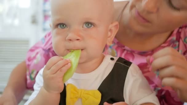 Mutter und Baby in einem schönen Kleid mit Schmetterling essen in einem Café auf der Straße. Kind isst ein Stück Gurkensalat Mutter — Stockvideo