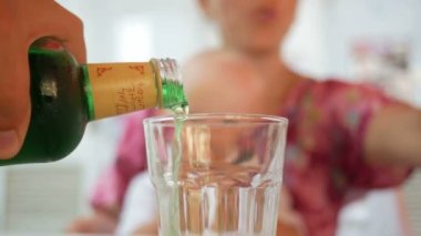Kelebek ile güzel bir elbise anne ve bebek sokakta bir kafede yemek. Yeşil elma limonata bir bardağa döküldü.