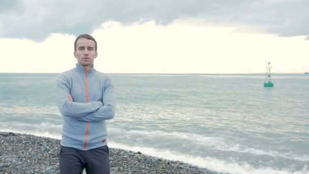 Schöner Mann am frühen Morgen am Strand, der in die Kamera schaut und lächelt. — Stockvideo