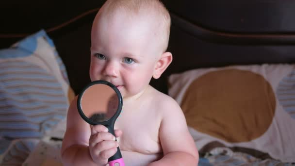 Beau bébé jouant avec peigne sur le lit. Souriez et essayez de vous peigner. Enfant 1 an. Sur le peigne est un miroir — Video