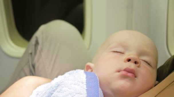 Μαμά και το μωρό ανάπαυσης στο αεροπλάνο κατά τη διάρκεια της πτήσης. Νυχτερινή πτήση πάνω από τον ωκεανό. Τα μάτια του παιδιού είναι κλειστά — Αρχείο Βίντεο