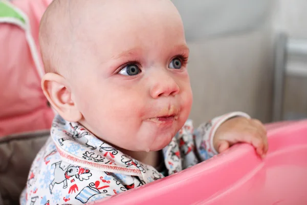 Hermoso bebé come gachas de la mano de las mamás. Está sentado en una silla rosa para niños. . — Foto de Stock