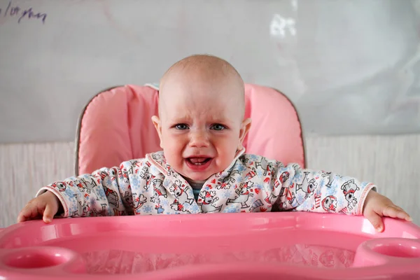 Hermoso bebé come gachas de la mano de las mamás. Está sentado en una silla rosa para niños. . — Foto de Stock