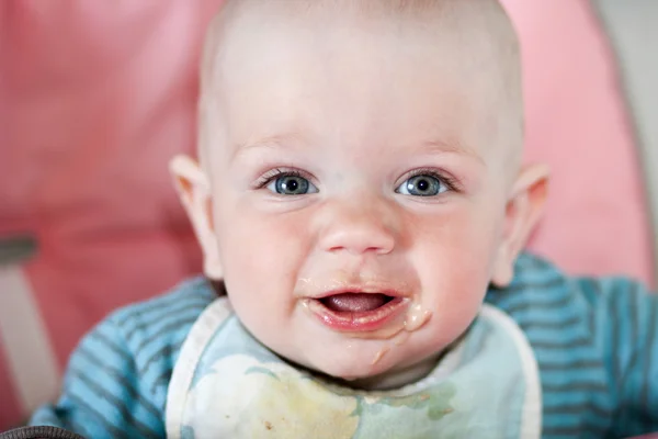 Hermoso bebé come gachas de la mano de las mamás. Está sentado en una silla rosa para niños. . — Foto de Stock