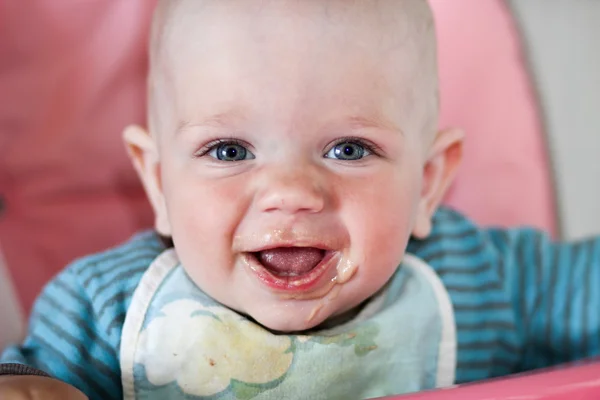 Hermoso bebé come gachas de la mano de las mamás. Está sentado en una silla rosa para niños. . — Foto de Stock