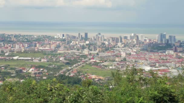 Une ville moderne avec des immeubles de grande hauteur et des maisons ordinaires. La forêt et la mer derrière — Video