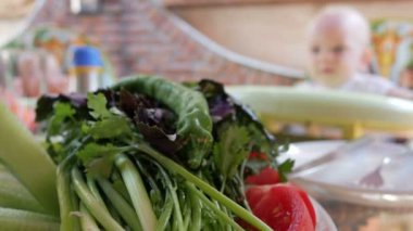 Yeşillik ve domates bir restoranda bir tabakta yalan. Bebek arka planı yiyor ve veliler ile görüşmeler