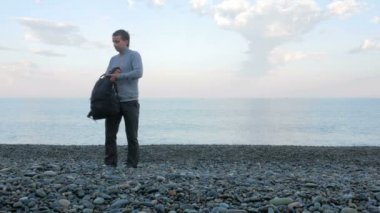 Kayalık sahile bir adam gelir ve okyanus çanta iyi telefon alır. O iş görüşmeleri yürüten