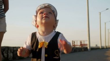 Genç anne ile şirin bebek oceanfront üzerinde günbatımında yürüme. Bebek hala çok kötüdür ve annem bu tutar çalışır. Hayattaki ilk adımları kavramı