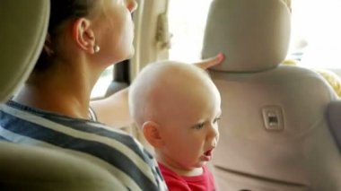 Arabanın arka koltuğunda çocuk ile anne gider. Sevimli küçük çocuk 1 yaşında anne kucağına gider ve etrafına bakıyor