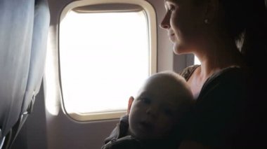 Annelerin kucak uçakta uçuş sırasında oturan bebek. Çevresinde ve kemer dokunmak görünüyor.