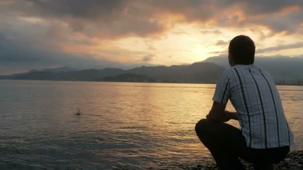 Güneş doğarken okyanus plaj üzerinde seyir gömlekli adam görünüyor. Güneşin dağların arkasından yükselir. Doğa hayranlık kavramı — Stok video