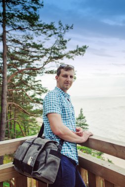 park ve gülümseyen ahşap merdivenlerde oturan adam