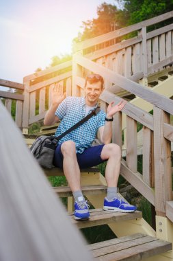 park ve gülümseyen ahşap merdivenlerde oturan adam