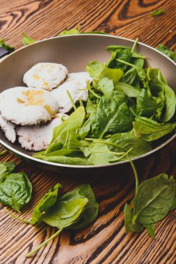 Ahşap bir masa yüzeyinde keskin bir mutfak bıçağı kullanarak ıspanak kesen kadın. Daha fazla ham taze yaprak kesilmeye hazır. Mutfak eylemleri konsepti