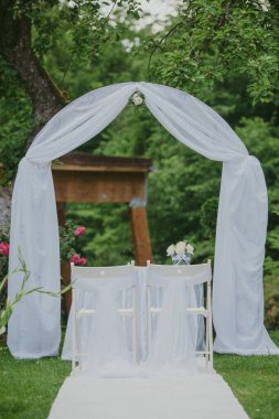 Açık havada düğün resepsiyonu. Süslü sandalyeler, çiçekler, mumlar.
