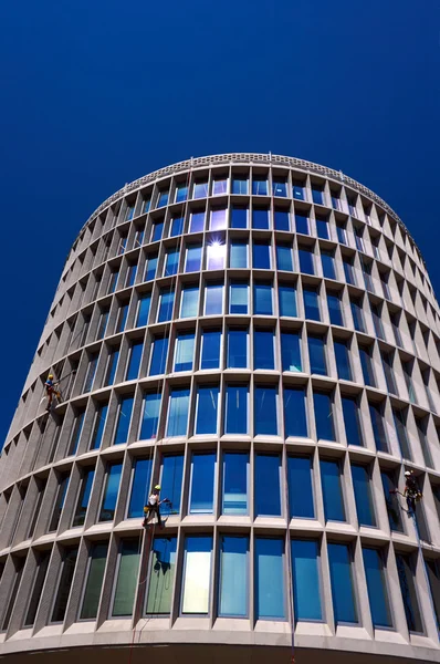 Чистка скляних вікон на фасаді модерніста, кругла будівля — стокове фото