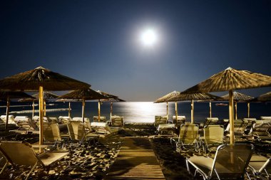 Yunanistan 'ın Zakynthos adasında gece vakti kumlu sahilde boş güneş pansiyonları ve şemsiyeler