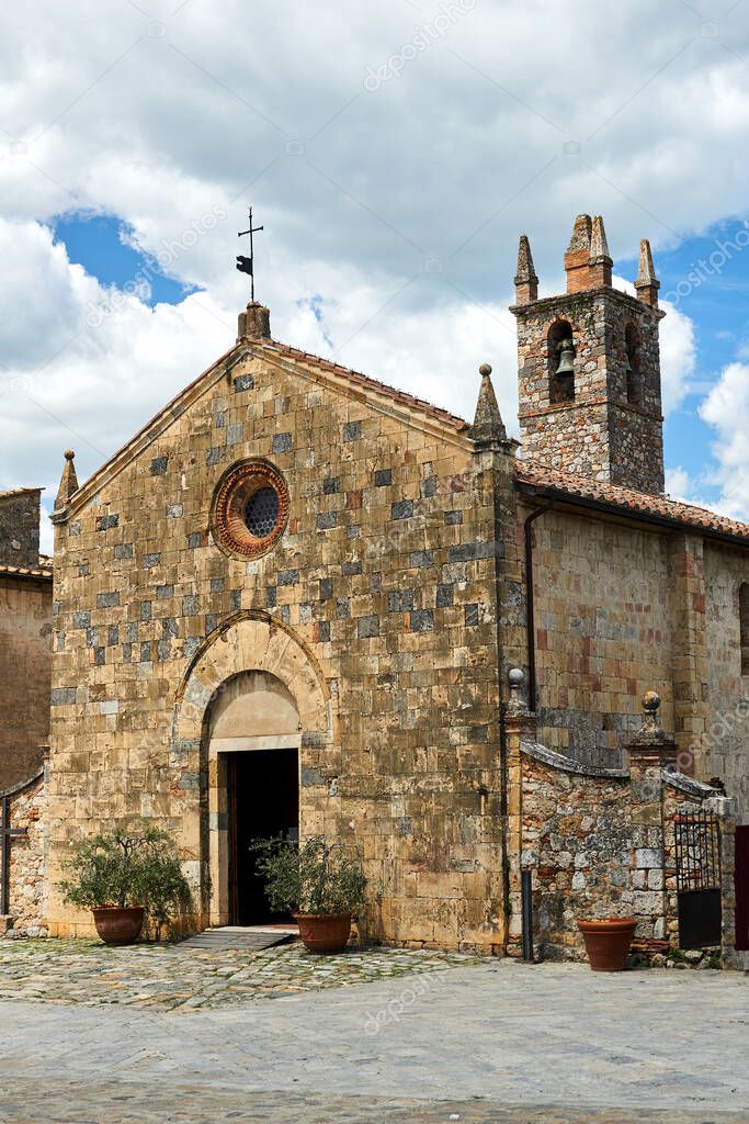 Stone, medieval church with a bell tower in the village of Monteriggioni in Toscana, Italy