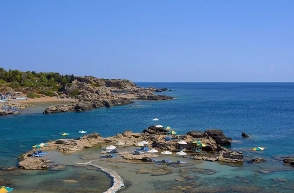 Sombrillas y camas de playa en las rocas — Foto de Stock