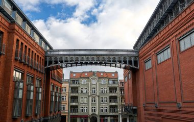 Polonya 'nın Poznan kentindeki tarihi bir apartman binasının ön cephesi ve eski bira fabrikasının metal yaya köprüsü.