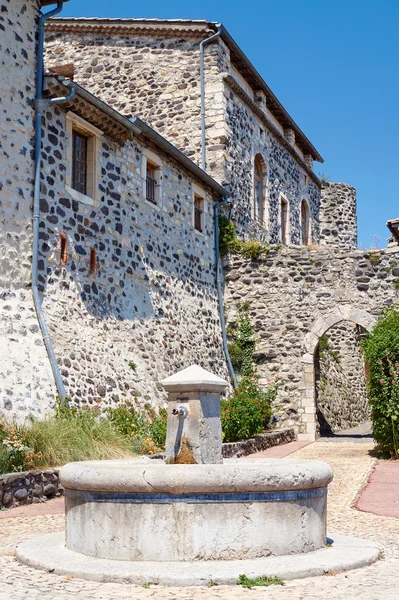 A stone well and medieval buildings in Saint-Vincent-de-Barres in France — Stock Photo, Image