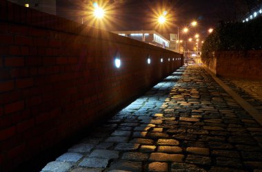 Yaktı ve geceleri Arnavut kaldırımlı sokakta Polonya Poznan şehri