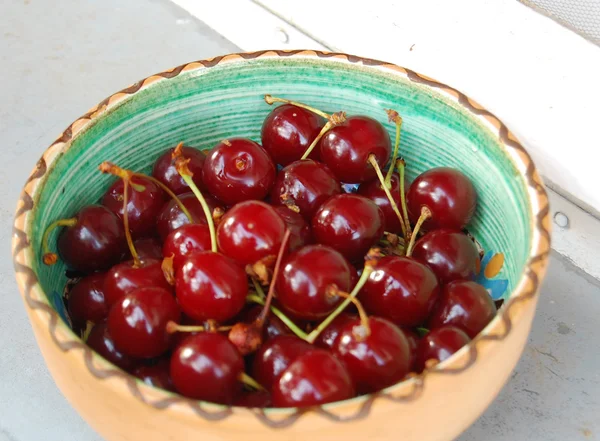 Свежие фрукты фон с кислыми вишнями в керамической миске — стоковое фото