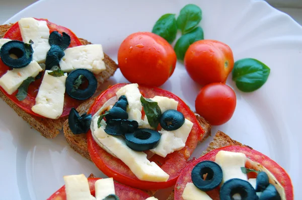 Bruschetta paradicsommal, olivával, kecskesajt, gyógynövények és olaj, pirított kenyér — Stock Fotó