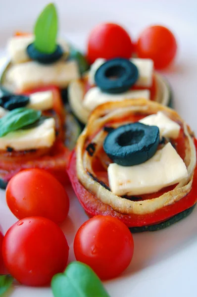 Grilled zucchini slices with tomatoes, black olives, goat cheese and basil — Stock Photo, Image