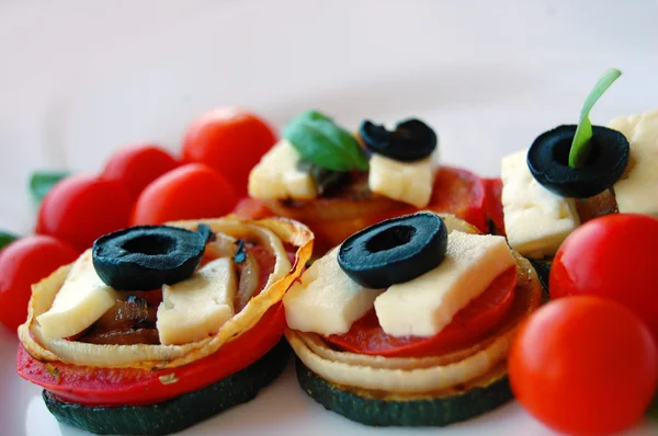 Шматочки кабачків на грилі з помідорами, чорними оливками, козячим сиром та базиліком — стокове фото