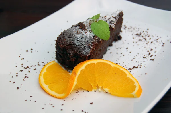 Brownie au chocolat sur une assiette blanche avec une tranche d'orange — Photo