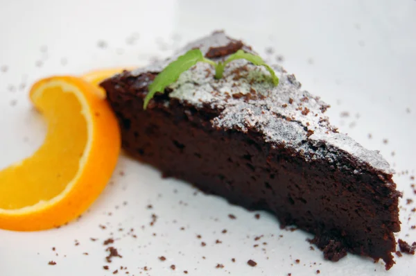 Chocolate Brownie on a white plate with slice of orange — Stock Photo, Image