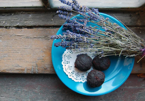 Eflatun bir tatlı tabağı ve ahşap arka plan üzerinde koyu çikolata truffles — Stok fotoğraf