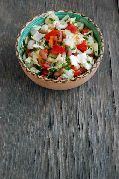 Свіжий салат з помідорами та капустою з петрушкою в керамічній мисці на сільському дерев'яному столі — стокове фото