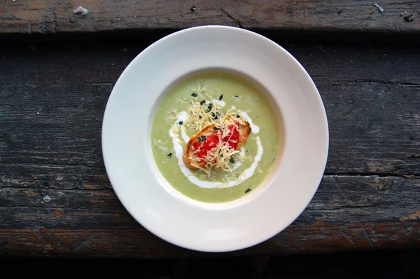 Close up of green pea soup with bread and cheese on top — Stock Photo, Image